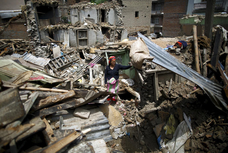 Image: A woman stands on the debris of collapsed houses after a fresh 7.3-magnitude earthquake struck Nepal, in Sankhu