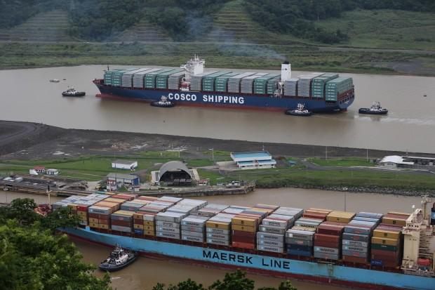 The COSCO Shipping Panama cargo ship, top, heads towards the new Cocoli locks, part of the new Panama Canal expansion project, as it cruises past another cargo ship passing through the old Pedro Miguel locks, in Panama City, Sunday, June 26, 2016. Authorities are hosting a big bash to inaugurate newly expanded locks that will double the Canal's capacity, as the country makes a multibillion-dollar bet on a bright economic future despite tough times for international shipping. (AP Photo/Dario Lopez-Mills)