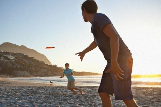 Father with son (7-9) playing frisbee on beach --- Image by © Felix Wirth/Corbis