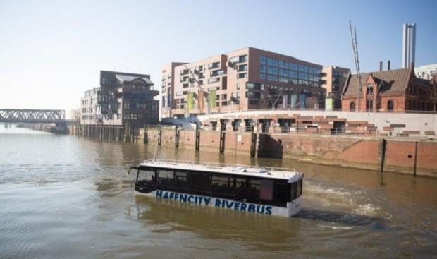 Ein Amphibienbus schwimmt am 17.03.2016 im Wasser durch die Hafencity in Hamburg. Der neue "HafenCity RiverBus" soll von April an Stadt- und Hafenrundfahrten für Touristen in Hamburg kombinieren. Foto: Christian Charisius/dpa +++(c) dpa - Bildfunk+++